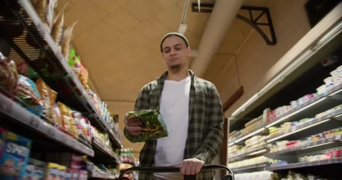 Mixed raced guy in the grocery store, put items to the cart randomly 動画素材 235347664