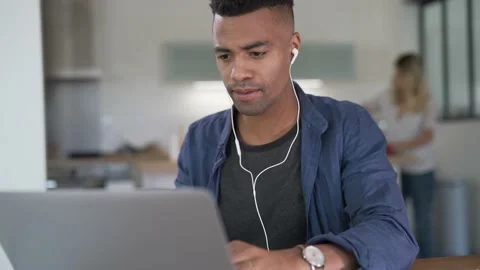Mixed-raced young man working from home on laptop Video stock 144607078