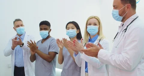 Mixed-races doctors and nurses medical team in masks clapping their hands to Stock Footage 144604284