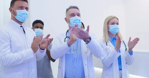 Mixed-races doctors and nurses medical professional team in masks clapping their Stock Footage 144604708