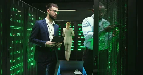 Mixed-races men checking server and tapping on tablet device. Software engineers Stock Footage 137547866