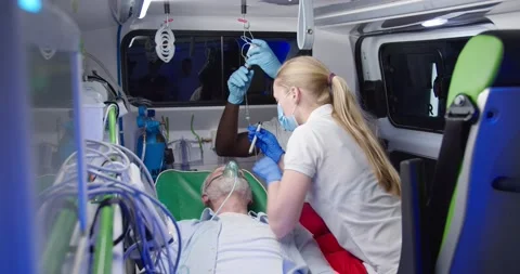 Mixed-races paramedics saving life of old man in ambulance. Medic giving oxygen Stock Footage 158309409