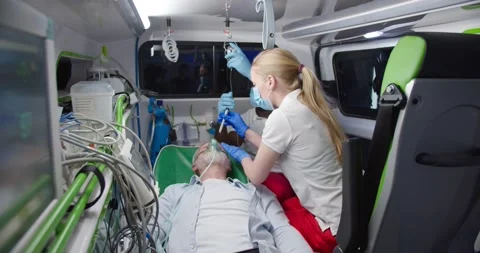 Mixed-races paramedics saving life of old man in ambulance. Medic giving oxygen Stock Footage 158309581