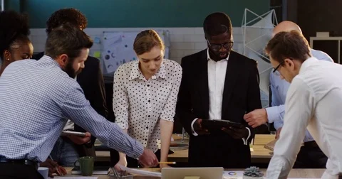 Mixed races team of co-workers leaning on a conference table while consulting Stock Footage 82446388