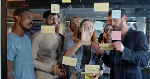 Mixed-races team of startup project talking about tasks and to-do notes and Stock Footage 180037754