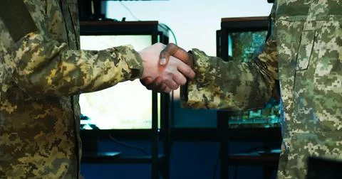 Mixed-races two militarian men in uniforms shaking hands as making deal at Stock Photos