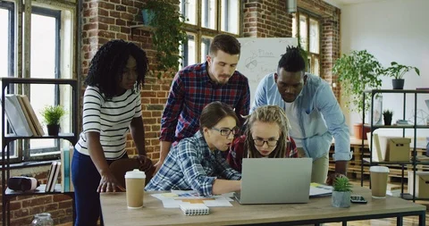 Mixed races young team being at the table with a laptop in the urban office zone Stock Footage 100992131