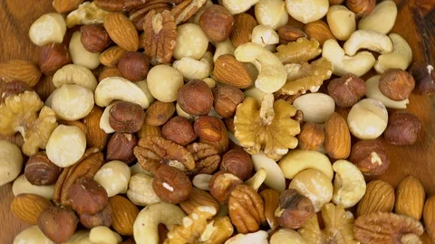 Mixed raw nuts piled on a rotating wooden plate Stock Footage 116271046