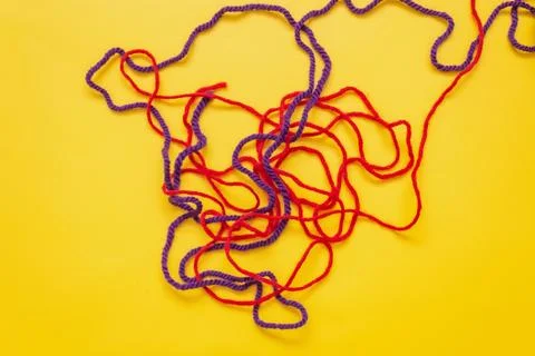 Mixed up red and blue wool threads lie on a yellow background Stock Photos