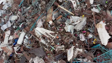Mixed scrap with broken baskets lies on dump ground while loose wire twists Stock Footage 321768447