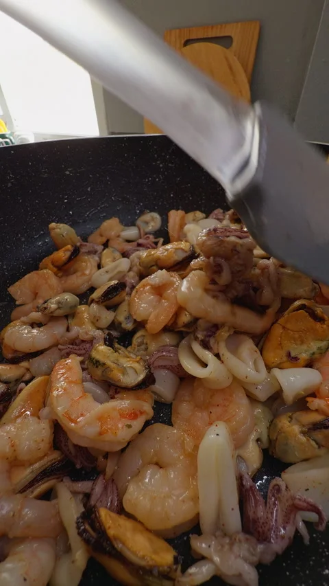Mixed Seafood Is Stir Fried in a Speckled Pan, Showing Shrimp Squid and Mussels Stock Footage 341979949