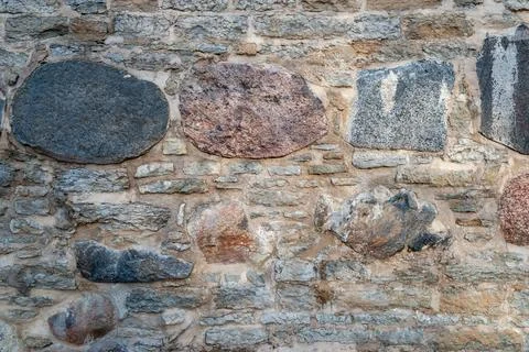 Mixed stone wall texture with varied rocks, natural masonry background Stock Photos