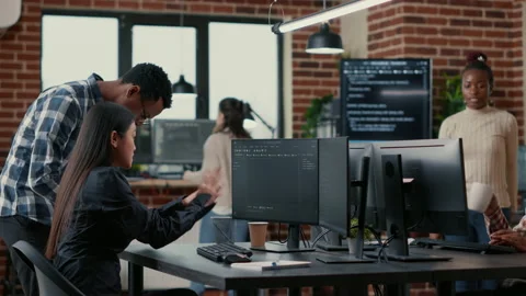 Mixed team of software developers analyzing source code pointing at screens Stock Footage 168251907