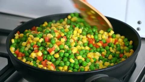 Mixed vegetables being stirred in frying pan on stove Stock Footage 331520654