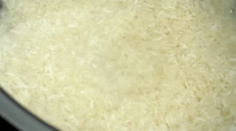 Mixed vegetables pouring down over uncooked rice covered with water ready for Video stock 62760459