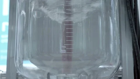 A mixer in a glass container prepares a solution for chemical reactions Stock Footage 187456565