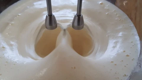 The mixer quickly turns in a plate with a liquid batter of eggs and milk. Cream Stock Footage 90808568