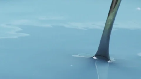 Mixing blue colored milk with spoon in 180fps slow motion Video stock 70693308
