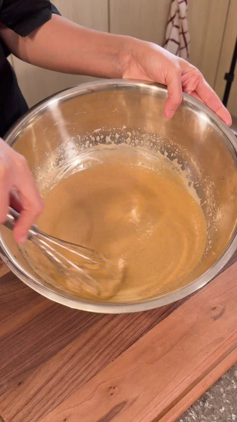 Mixing Cake Batter with Balloon Whisk in Stainless Steel Bowl Stock Footage 331034462