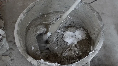 Mixing cement for construction in a small black tank. Worker mixing plaster i Video stock 125951019