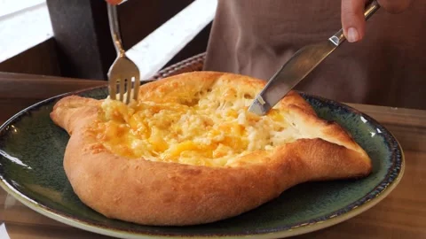 Mixing cheese and egg in hot Adjarian Khachapuri in a cozy restaurant Stock-Footage 284576491