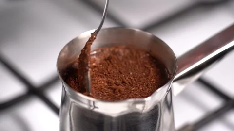 Mixing coffee with teaspoon while preparation in turkish coffee pot Stock Footage 148976553