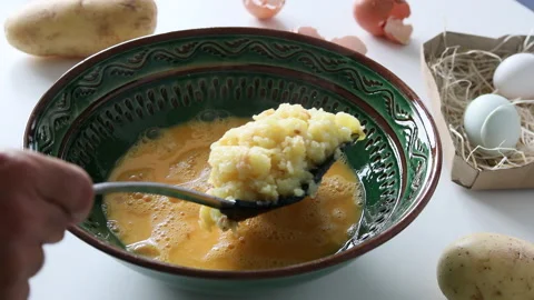 Mixing the cooked potato with the eggs to prepare a Spanish omelette. Stock Footage 197118719