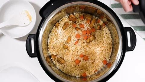 Mixing cooked rice, vegetables, and meat in a pot. Stock Footage 124473752