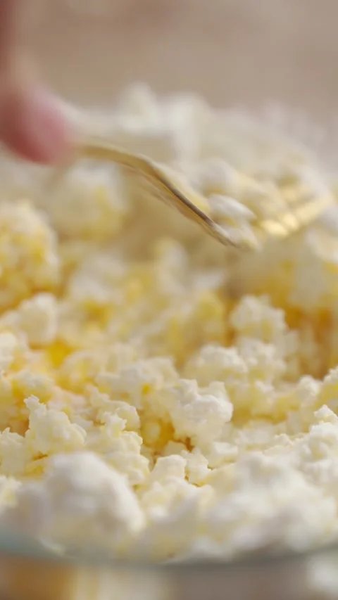 Mixing cottage cheese mixture with a fork, hand stirs soft curds and egg Stock Footage 336928658