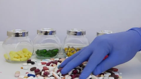 Mixing different colors tablets and picking up one white tablet from bunch Video stock 147699789