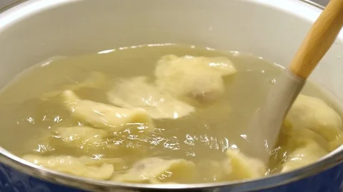 Mixing dumplings in a pan while cooking Stock Footage 122096679