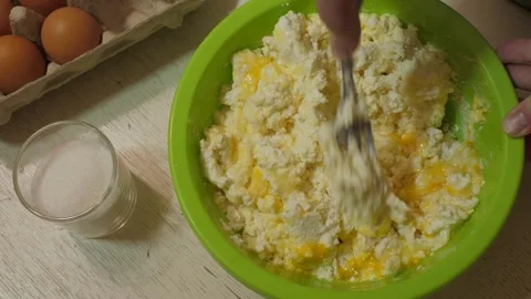 Mixing eggs with cottage cheese in a green bowl Video stock 342361563