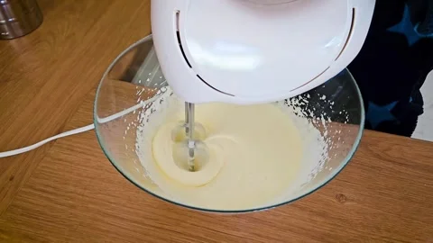 Mixing Eggs With Hand Mixer to Prepare Creamy Batter in Cozy Kitchen Setting on Stock Footage 303705451