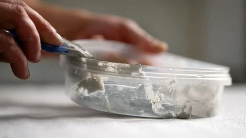 Mixing epoxy grout by hand in a clear plastic container using a blue spatula. Stock Photos