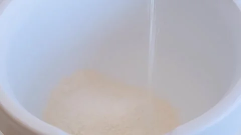 Mixing flour with egg, close-up, on a black background. Preparing the dough. Stock Footage 285420297
