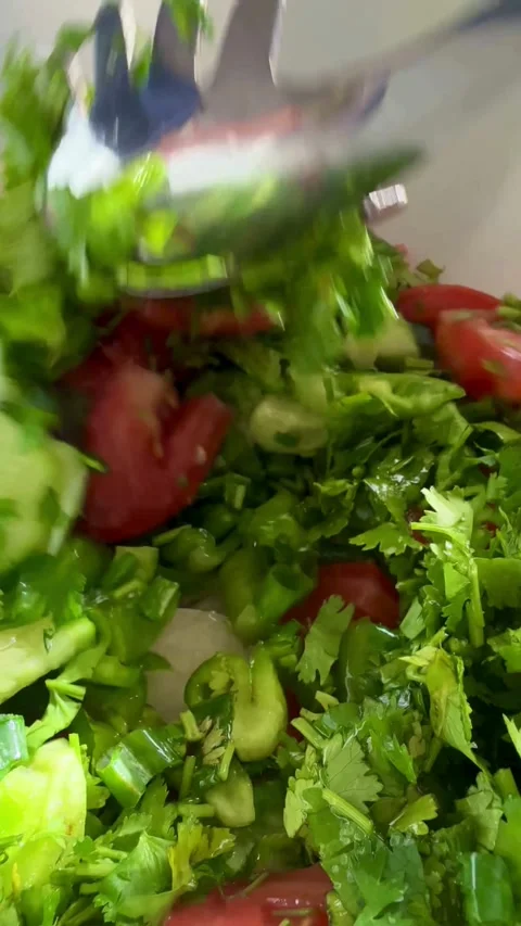 Mixing a fresh vegetable salad with cilantro and server Stock Footage 331976583