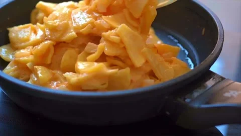 Mixing fried potatoes with eggs to make Spanish omelette (tortilla de patatas) Stock Footage 250566919