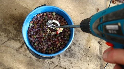 Mixing a grape mixture in a bucket with a tool Stock Photos