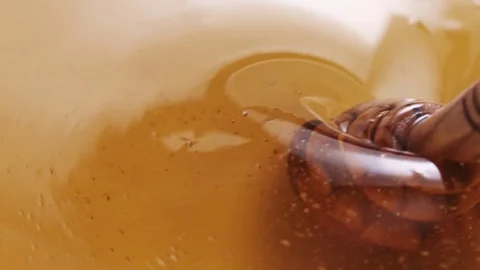 Mixing honey with wooden dipper in slow motion Stock Footage