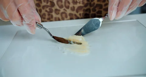 Mixing lipstick base on glass surface with spatulas Stock Footage 314601766