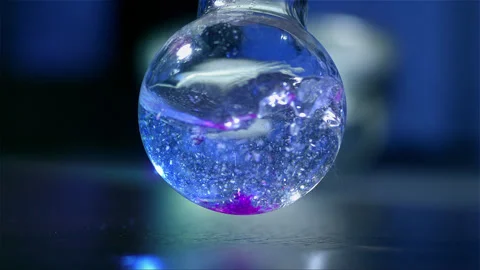Mixing liquid in a glass round laboratory flask in slow motion Stock Footage 257030847