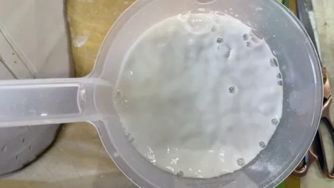 Mixing liquid plaster in a measuring jug for pouring into botanical clay mold. P Stock Footage 314186799