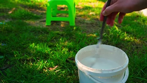 Mixing liquid for treating tree trunks in a bucket, close-up. Preparing for care Stock Footage 302277643