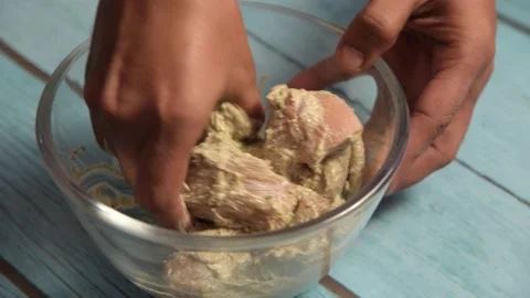 Mixing marinated chicken using hands in a glass bowl Video stock 166091240