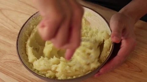 Mixing mashed potatoes in bowl while adding liquid for creamy texture. 库存影片 332826837