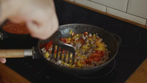 Mixing minced meat with red and yellow peppers in skillet Stock Footage 315243701
