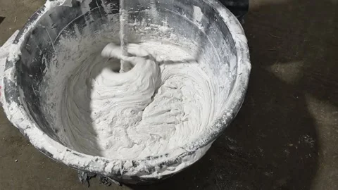 Mixing plaster in a bucket for building projects at a construction site in the a Stock Footage 326374571