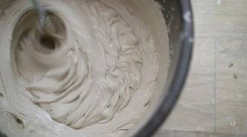 Mixing plaster solution in a bucket, using an electric drill. Mixing beige putty Stock Photos