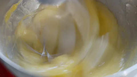 Mixing raw eggs in a silver kitchen stand mixer. Whipping the eggs. Slow motion. Stock Footage 233010513