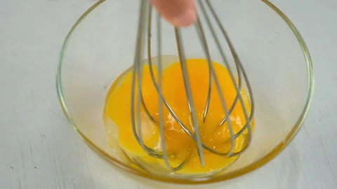 Mixing salt with egg yolk using whisk in glass bowl cooking food on kitchen. Stock Footage 313127075